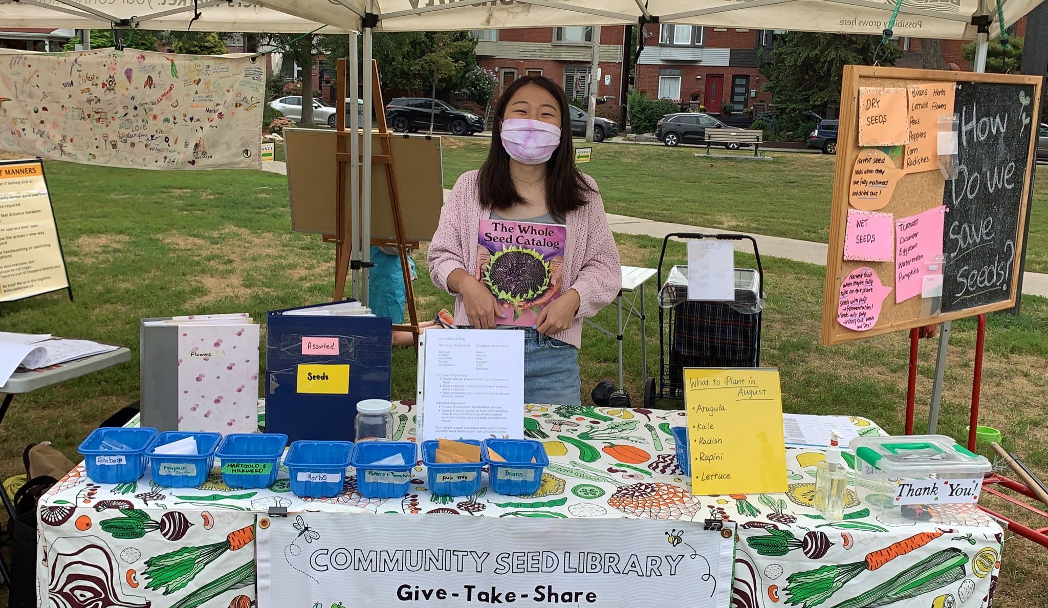 A volunteer Seed Librarian stands at the Seed Library booth